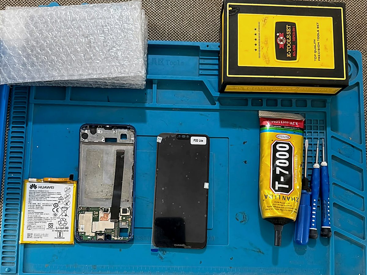 Huawei P20 Lite desarmado sobre el tapete de trabajo, con batería, chasis y pantalla separados